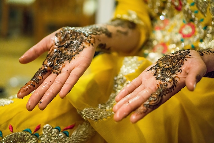 Hermoso retrato de boda de las manos decoradas de una novia india posando en traje tradicional - Fotografía de boda india