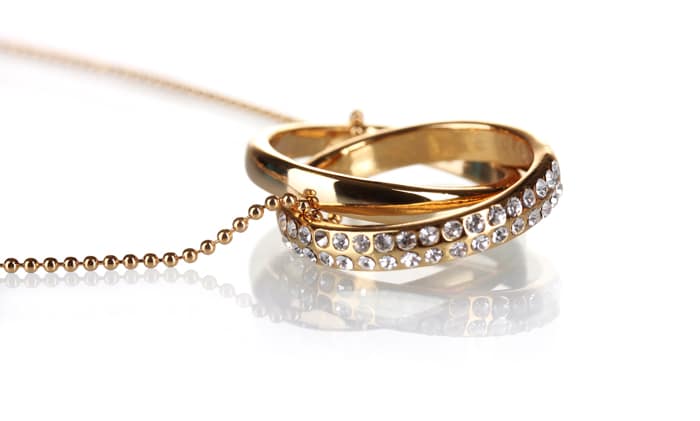 Foto de producto de joyería de collar de oro y una medalla de oro con christals sobre fondo blanco.