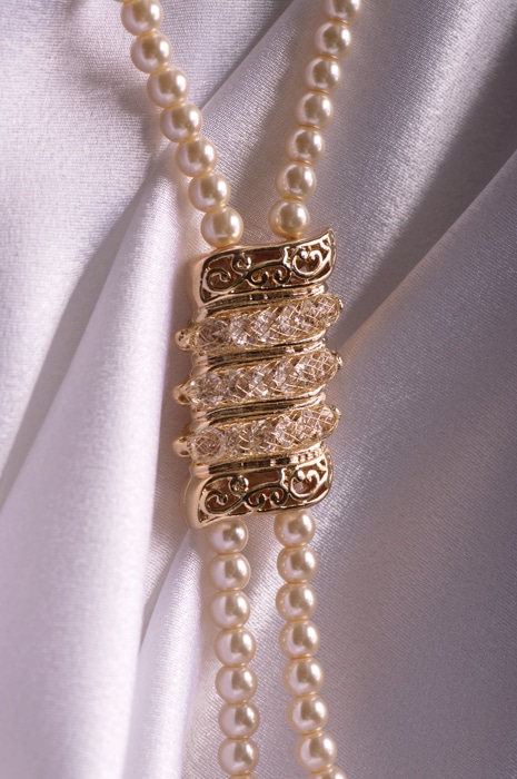 collar de perlas sobre fondo de seda con una medalla de oro