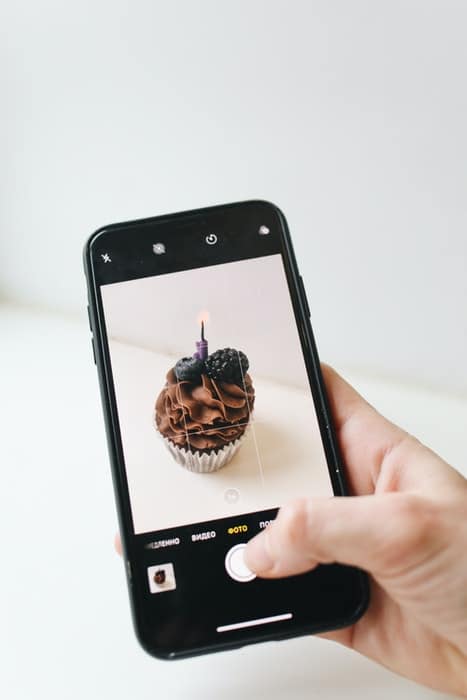 Una persona que toma una foto de un muffin de chocolate con una cámara de iphone
