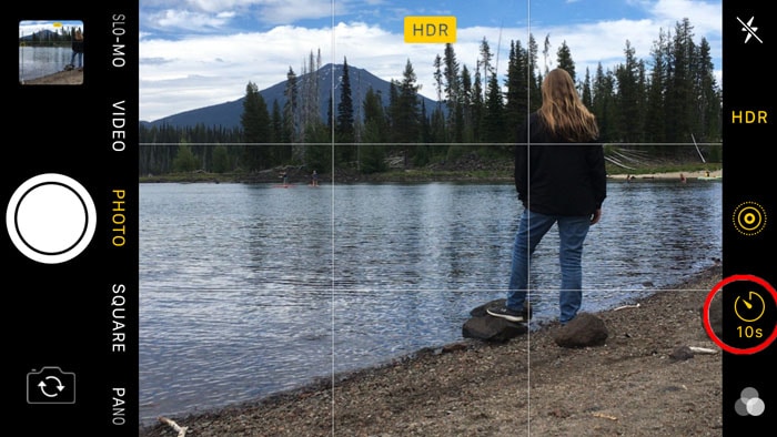 Captura de pantalla del uso del temporizador automático de iphones para tomar una foto de una niña de pie junto a un lago