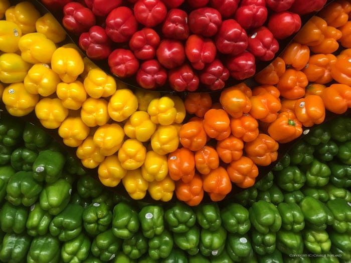 Muchos pimientos verdes, amarillos, rojos y naranjas ordenados por color