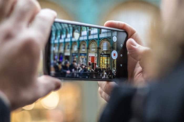 una persona que toma una foto en la calle con un teléfono inteligente: cámara iphone vs android