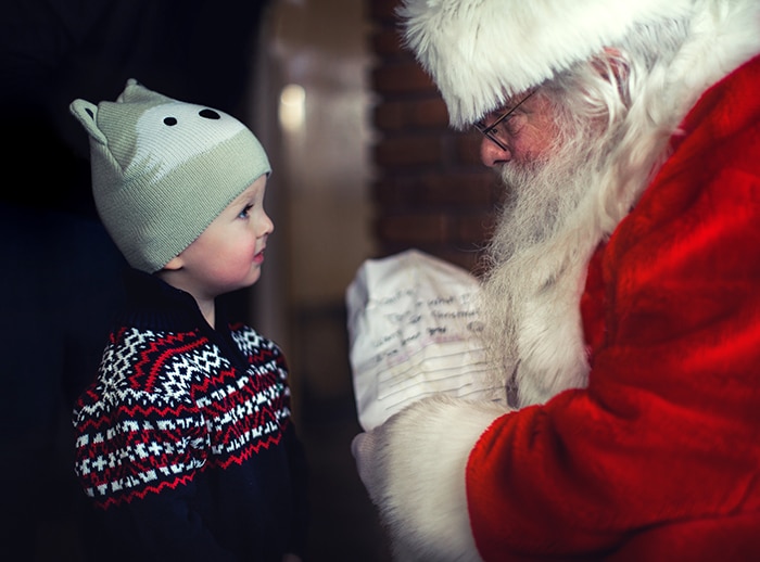 Un retrato de Navidad en interiores de un niño que se encuentra con un Santa Claus