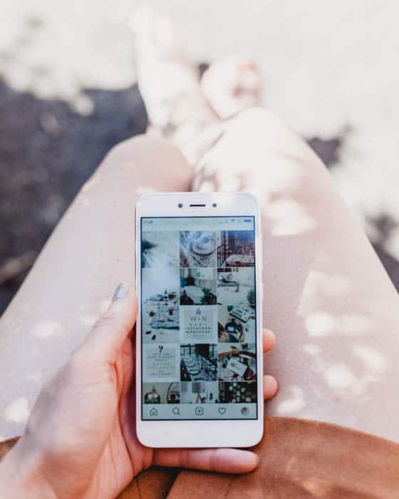 Una persona sosteniendo un teléfono inteligente y cargando fotos en Instagram.