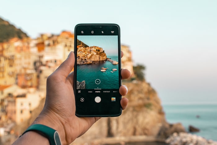 foto de alguien tomando una foto de una hermosa costa con un teléfono inteligente