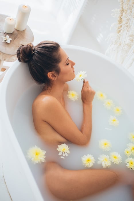 Una sesión fotográfica íntima de baño de leche con flores.
