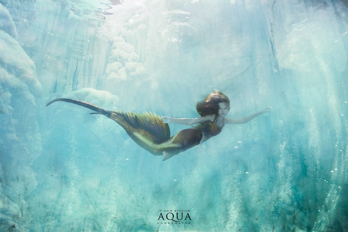 Una mágica sesión de fotos de sirenas bajo el agua con una modelo femenina con cola de sirena nadando bajo el agua