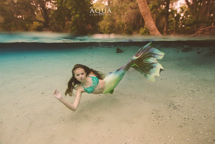 Una mágica sesión de fotos de sirenas bajo el agua con una modelo femenina con cola de sirena nadando bajo el agua