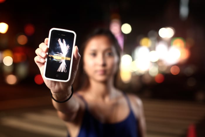 Una mujer sosteniendo un teléfono inteligente, el teléfono está enfocado, mientras que el resto de la imagen está borrosa