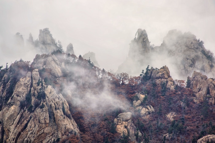 Montañas cubiertas de niebla tomadas con zoom completo en un objetivo de 300 mm con una cámara réflex digital de fotograma completo.
