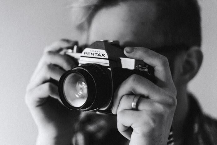 Fotografía en blanco y negro de un chico sosteniendo una cámara
