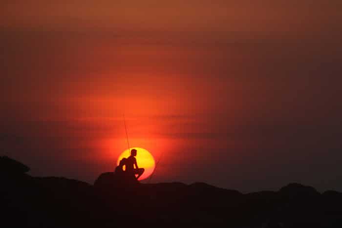 Siluetas de dos personas sentadas en las rocas al atardecer - fotografía de naturaleza minimalista