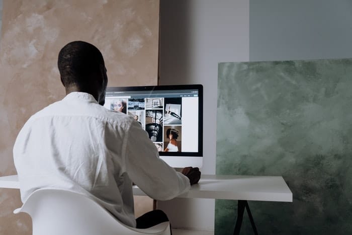 Hombre sentado junto a una computadora con imágenes en la pantalla