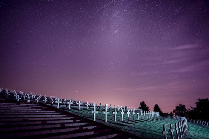 Una foto nocturna de un cementerio bajo un cielo estrellado.