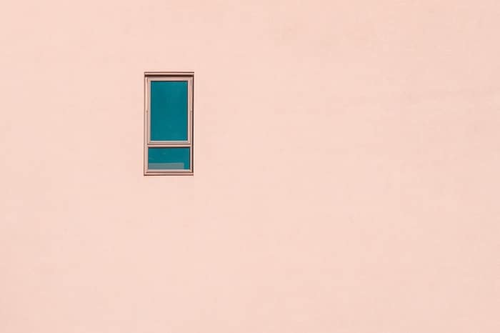 fotografía minimalista de una pequeña ventana en la fachada de un edificio rosa