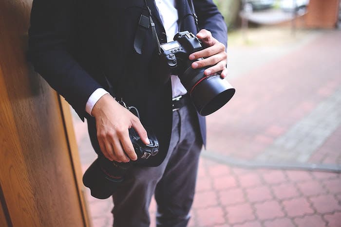 Un primer plano de un fotógrafo profesional sosteniendo una DSLR en una sesión de fotos
