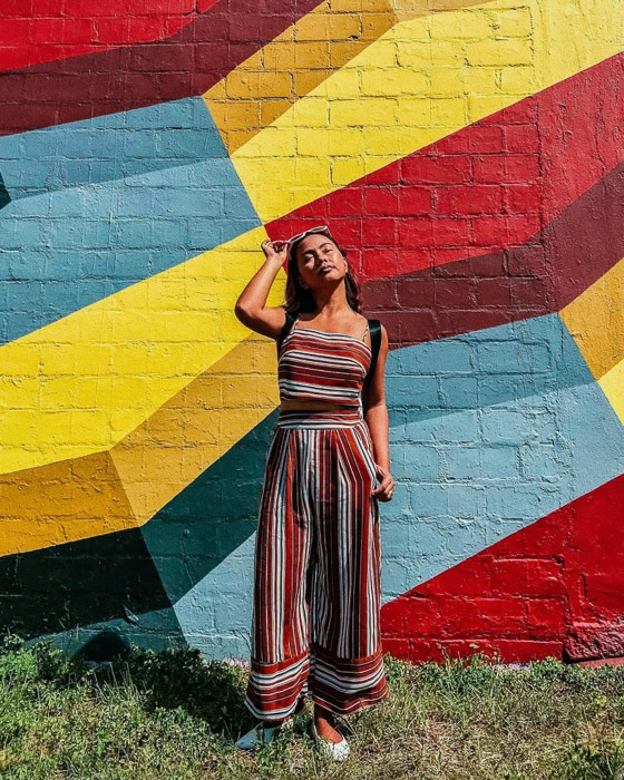Una modelo femenina posando junto a una pared multicolor tomada con un temporizador de fotos de iphone