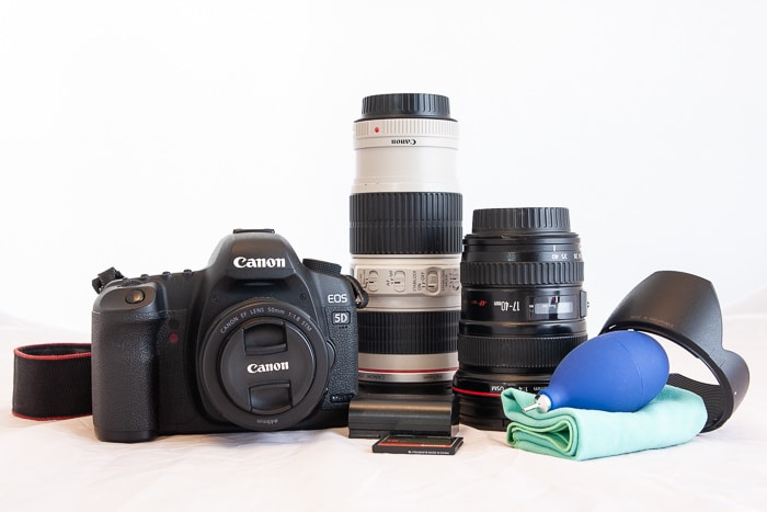 Un bodegón de una cámara Canon y otros equipos de fotografía sobre un fondo blanco.
