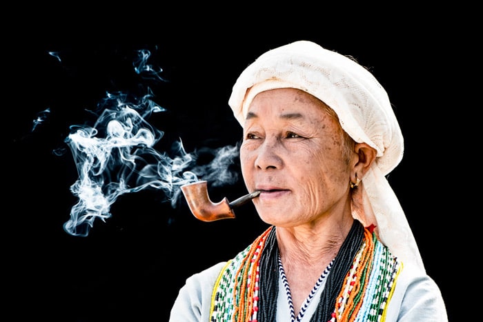 Un retrato de un hombre Karen fumando en pipa contra un fondo negro - errores de iluminación de la fotografía