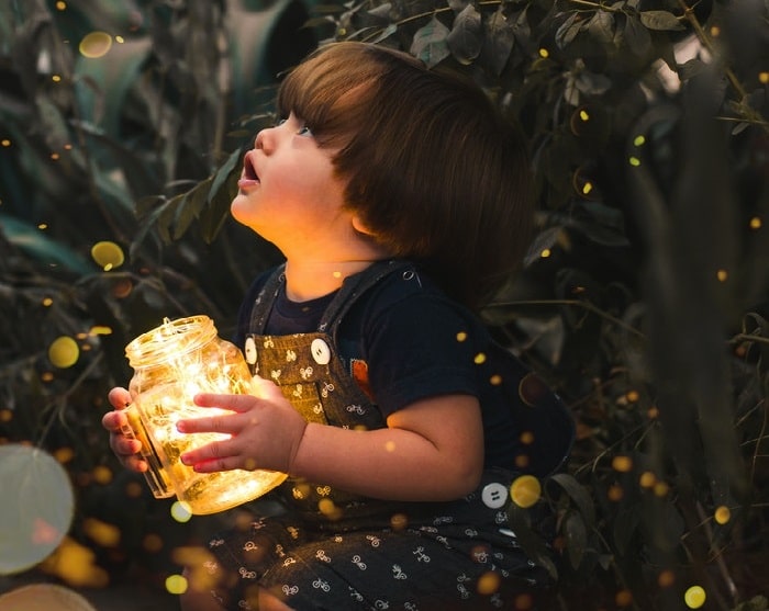 Niño sosteniendo un frasco con luces de hadas capturadas con efecto de fotografía bokeh
