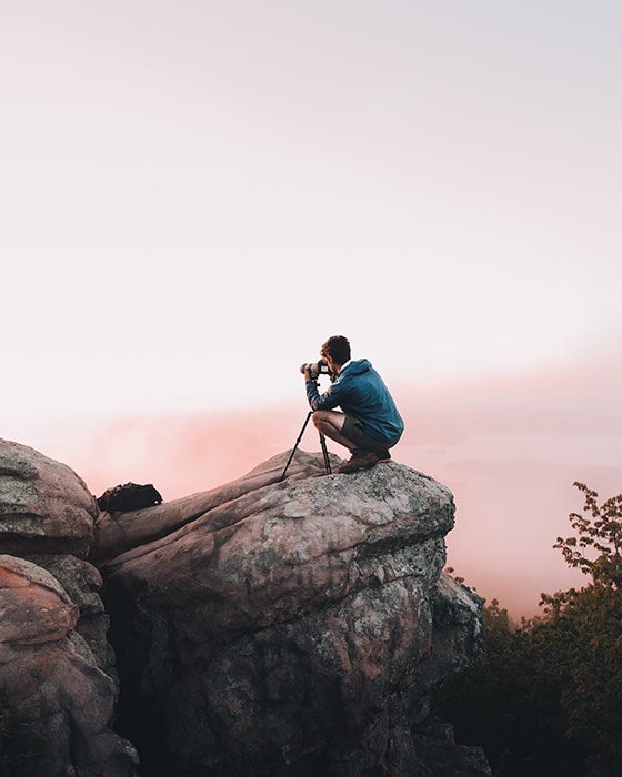Foto de un hombre tomando una foto sobre una roca