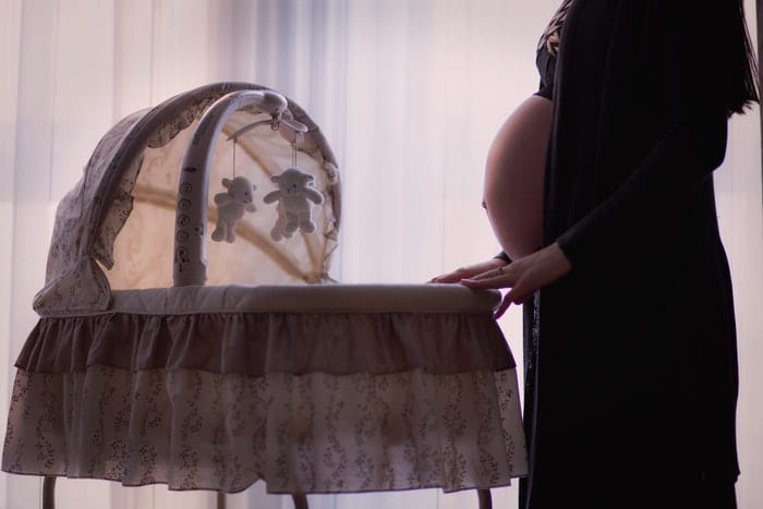 Hermosa foto de tocador de maternidad de una mujer embarazada meciendo una cuna