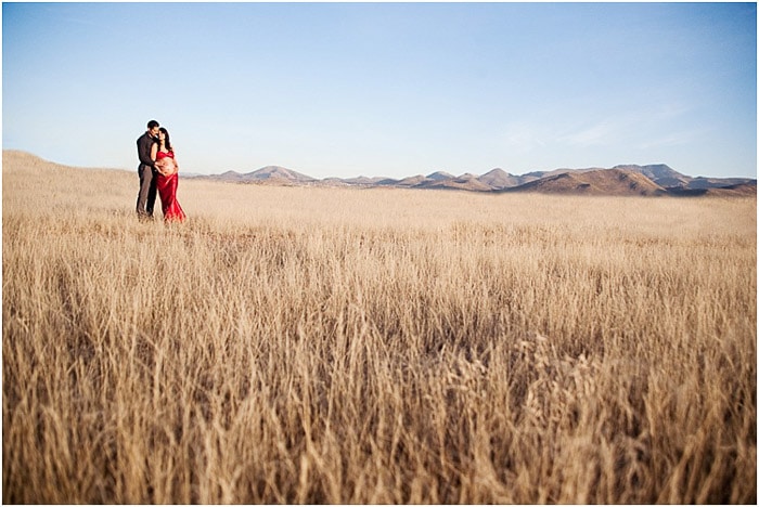 Una pareja posa juntos en un tranquilo paisaje de maizal demostrando poses de fotografía de maternidad