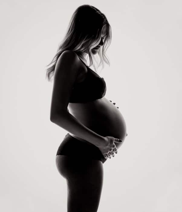 Hermosa foto de tocador de maternidad de una mujer embarazada posando en ropa interior