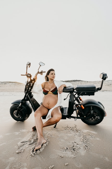 Una mujer embarazada posando en lencería en una moto