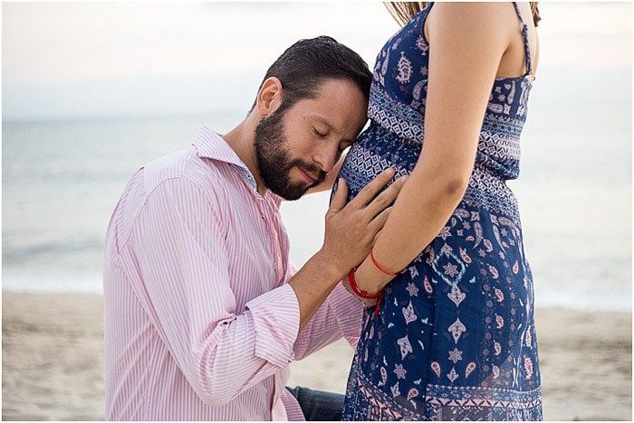 Sesión de fotos de maternidad dulce del padre sosteniendo el vientre de su esposa en una playa
