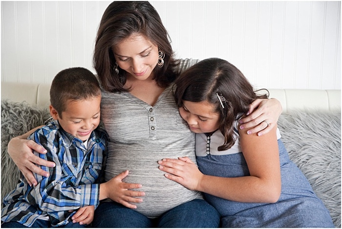 Hermosa fotografía de maternidad de dos niños, niño y niña, mirando y tocando el vientre de la madre embarazada