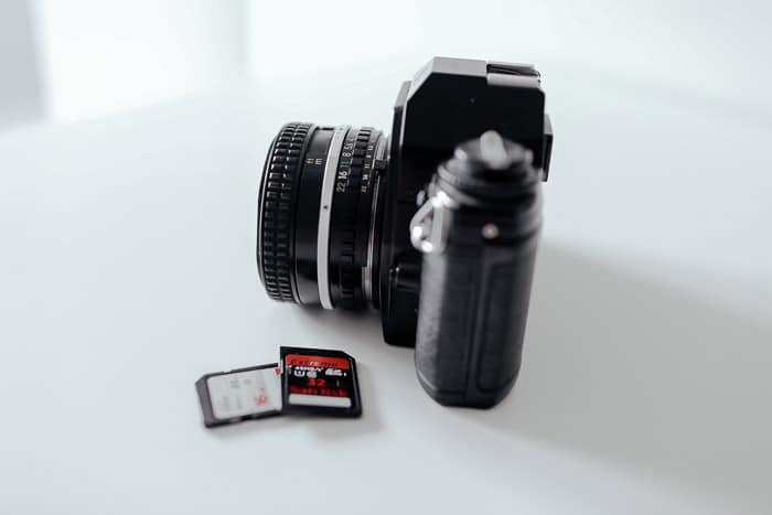 Una cámara junto a dos tarjetas de memoria sobre fondo blanco.