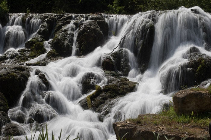 Hermosa cascada que fluye con una larga exposición para crear un desenfoque de movimiento con el movimiento del agua e implicar fluidez.