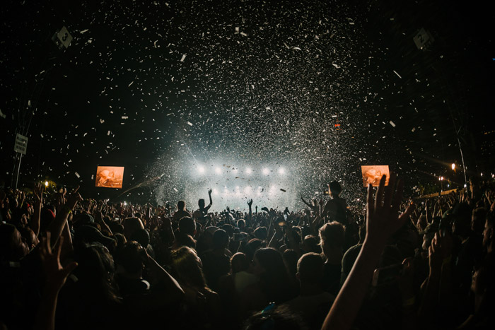 una gran multitud viendo un concierto con poca luz: consejos de fotografía para festivales de música