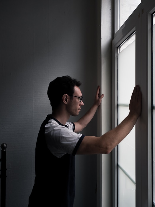 un retrato de un hombre mirando por una ventana, iluminado con una sutil iluminación dividida