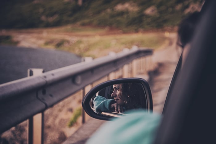 el reflejo de una mujer joven en el espejo lateral de un automóvil