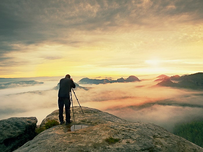 Un hombre disparando imágenes de niebla en un paisaje.