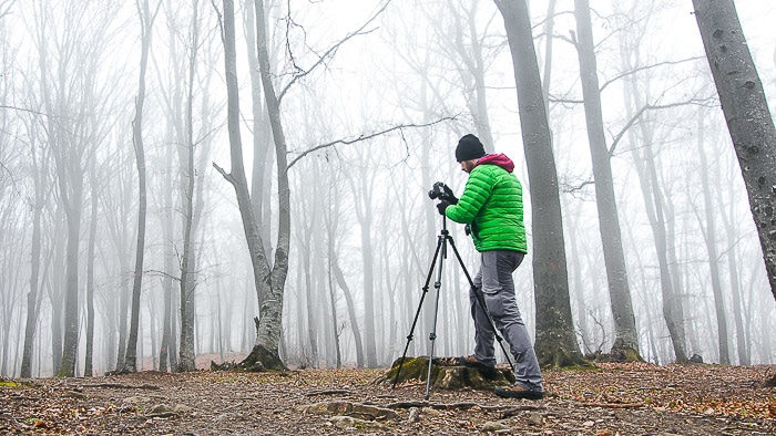 Un hombre disparando fotografías de niebla en un bosque