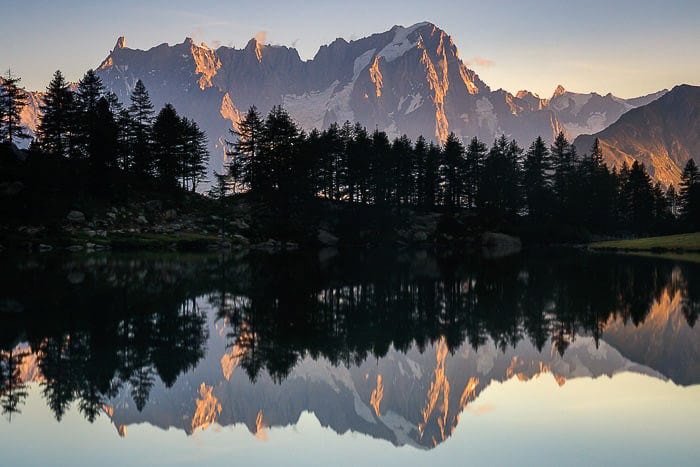 Hermosa exposición larga de árboles y montañas que se reflejan en un lago