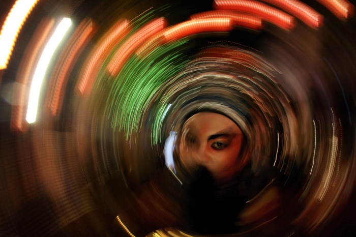 Una persona mirando a través de un túnel de luces de colores arremolinadas