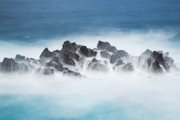Brumoso sobre rocas en el océano capturado a través de una exposición prolongada 