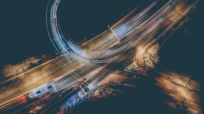 Magnífica fotografía aérea de doble exposición de una autopista con estelas de luz de colores 