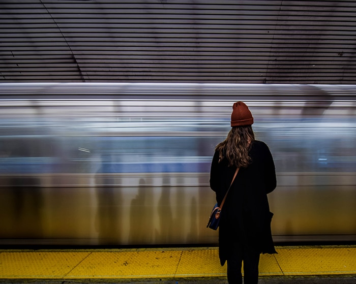 Una mujer se para frente a un tren en movimiento.