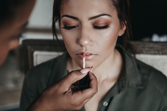 Retrato de un modelo femenino aplicando lápiz labial para una sesión de fotografía de maquillaje