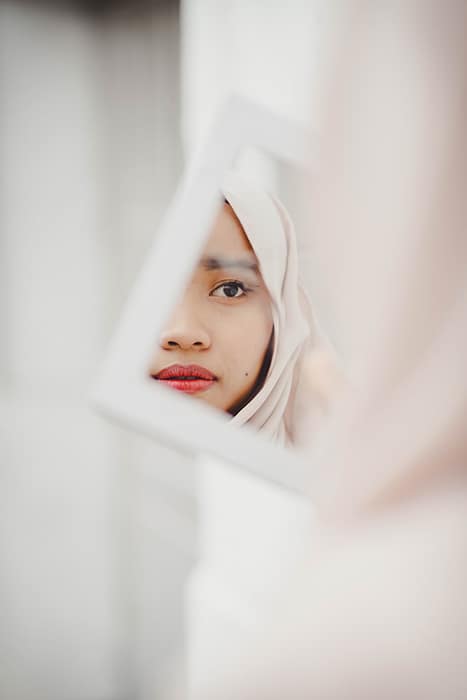 Impresionante retrato de una hermosa modelo femenina posando en un espejo para una sesión de fotografía de maquillaje
