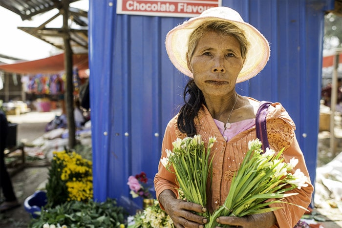 Una foto de una vendedora del mercado que vende flores, cómo crear una fotografía de fondo blanco