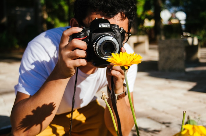 Un hombre que toma una foto macro de una flor amarilla - consejos de iluminación de fotografía macro