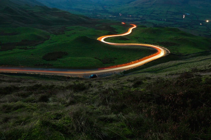 Larga exposición de estelas de luz en una carretera sinuosa.
