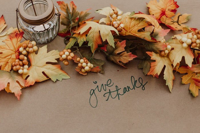 Una fotografía plana de acción de gracias con hojas de otoño y una vela.